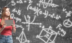 Young lady is pondering about complicated math problem. Formulas and graphs are drawn on the black chalk wall.